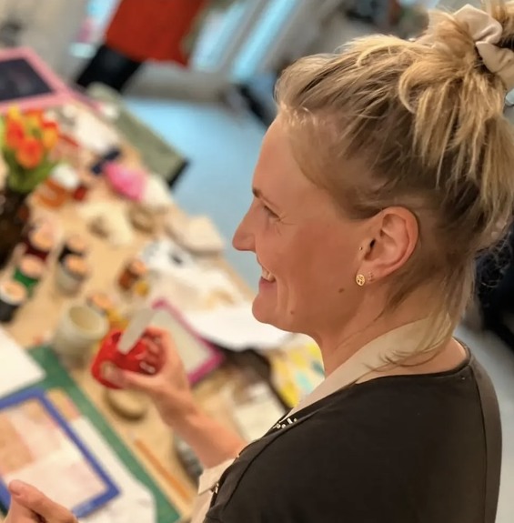 Sarina gestaltet lächelnd ein Werkstück an ihrem Basteltisch.